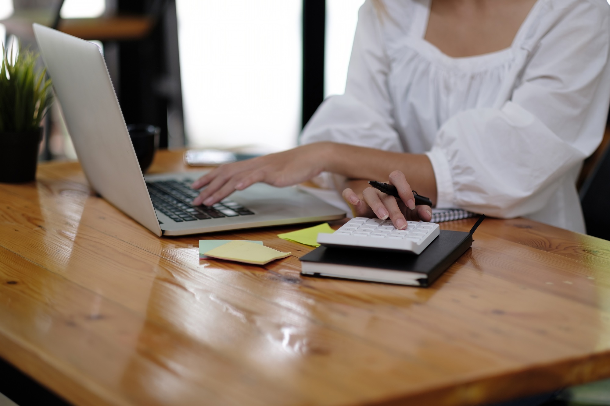 Business woman using calculator to calculate the numbers in the company financial documents, the
